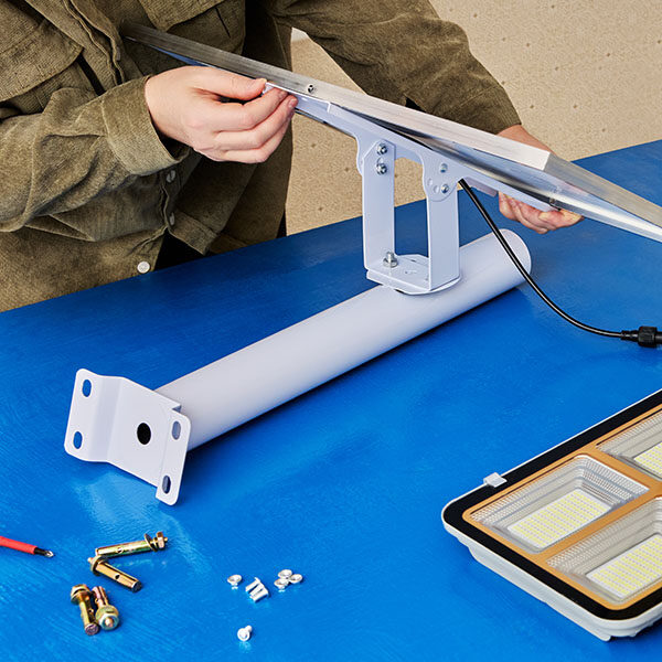 Assembler attaches solar panel to mounting bracket holder for self-contained, cordless LED street light.